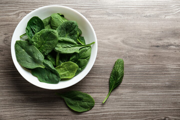 Fresh green healthy spinach leaves on wooden table, flat lay. Space for text