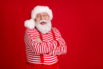 Profile photo of pensioner old man folded hands self-assured empty space laugh kid story wear santa costume suspenders spectacles striped shirt headwear isolated red color background
