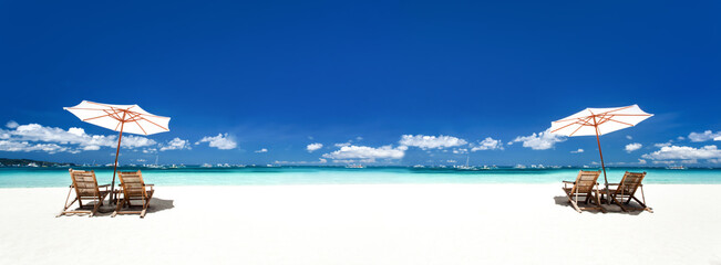 Sun umbrellas and wooden beds on tropical beach. Caribbean vacation on tropical shore