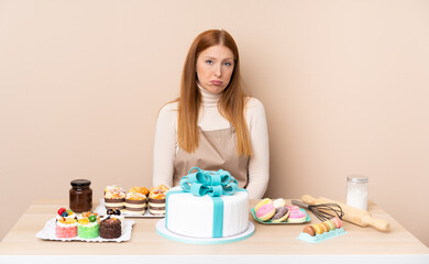 Obraz na płótnie Canvas Young redhead woman with a big cake sad