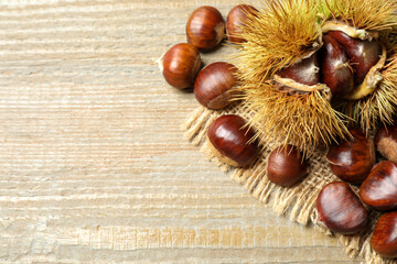 Fresh sweet edible chestnuts on wooden table, flat lay. Space for text