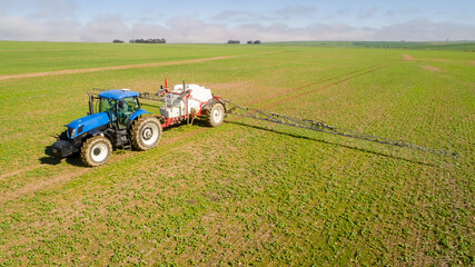 Obraz premium Wide angle image of a crop spray machine spraying chemicals on wheat crop on a farm in south africa
