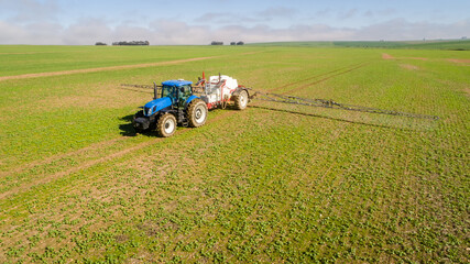 Wide angle image of a crop spray machine spraying chemicals on wheat crop on a farm in south africa