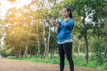 Female runner using smart watch to monitor performance. Sport women is setting up her smart watch before running in the morning