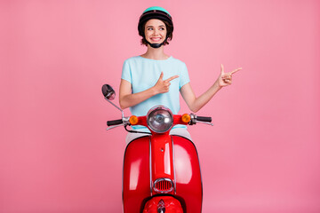 Photo of cheerful nice positive young lady ride red moped point empty space wear blue outfit slam...