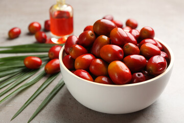 Palm oil fruits in bowl on grey table, closeup