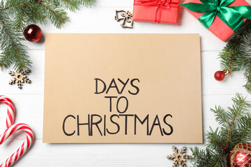 Flat lay composition of card with words Days To Christmas and space for text on white wooden table....