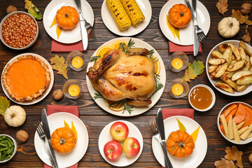 Traditional Thanksgiving day feast with delicious cooked turkey and other seasonal dishes served on wooden table, flat lay