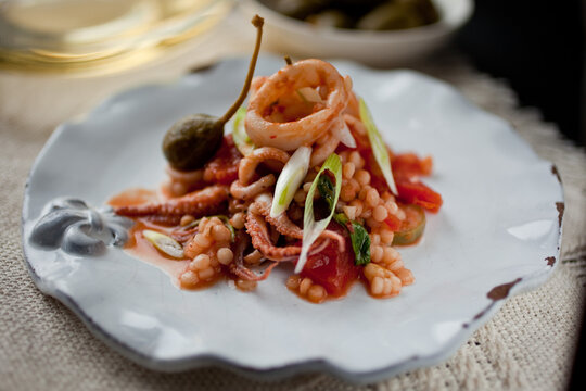 Close up of calamari with tomato, caperberries and pine nuts