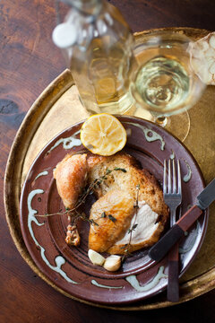 Chicken with thyme and garlic on plate with champagne glass