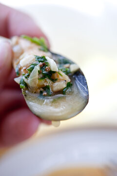 Hand holding ale steamed mussel with garlic and mustard