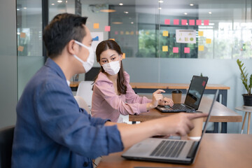 Asian workers in offices wear face masks to prevent the spread of COVID-19. Working in the new normal era and Social distance.