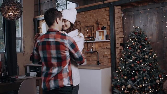 Crazy young couple dancing and having fun on Christmas evening. Brightly decorated living room decorated with bright Christmas tree lights. Happy winter holidays and hobby concept