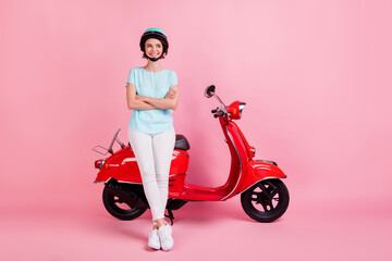 Fototapeta na wymiar Photo of positive pretty young lady stand moped crossed arms wear white trousers footwear blue slam t-shirt isolated on pink background
