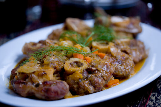 Close up of cooked meat with onion and carrot on platter