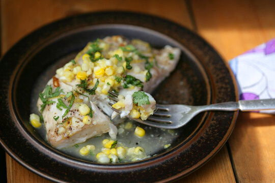 Gourmet Cooked Fish With Corn And Herbs On Top On Plate