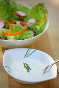 Garlic sauce with chives in dip bowl and salad in background