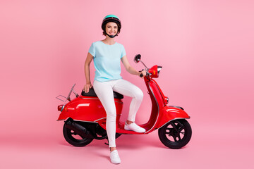 Fototapeta na wymiar Photo of cheerful nice funny young women sit moped wear white trousers sneakers blue slam t-shirt isolated on pink background