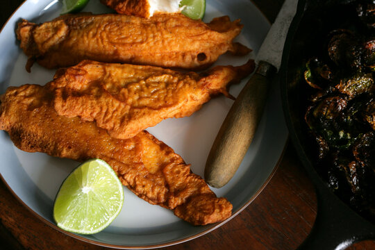 Golden battered fried fish fillets with lime on plate