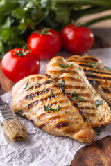 Grilled chicken breast on butcher board close up