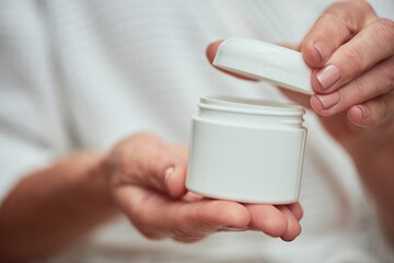 Woman opening cream bottle with manicured hands