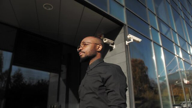 Confident black man walking on street in city at sunny day. Portrait African american handsome businessman.
