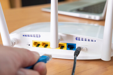 Selective focus at router antenna while men hand connecting fiber cable plug into socket with...