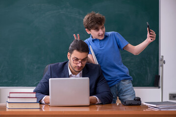 Young male teacher and schoolboy in the classroom