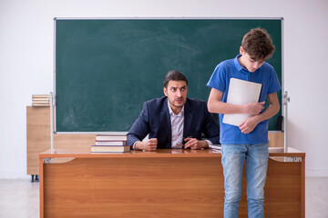 Young male teacher and schoolboy in the classroom