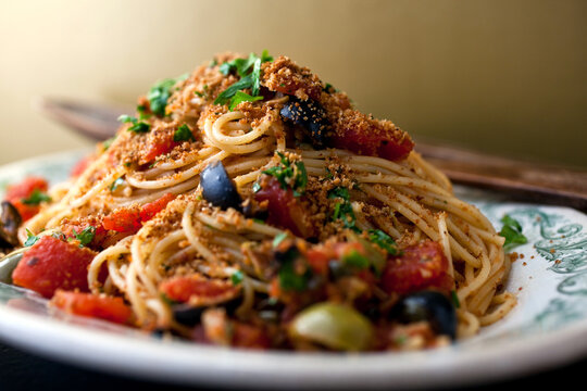 Close up of pasta with tomatoes, capers, olives and breadcrumbs