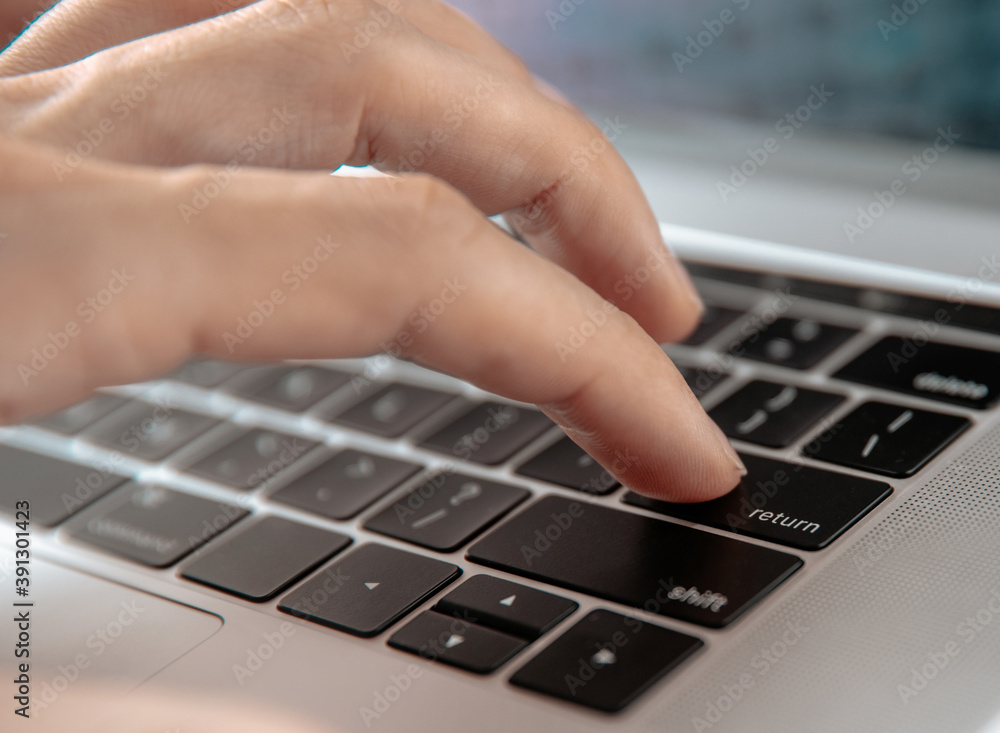 Wall mural close up. man pressing the enter key on his laptop.