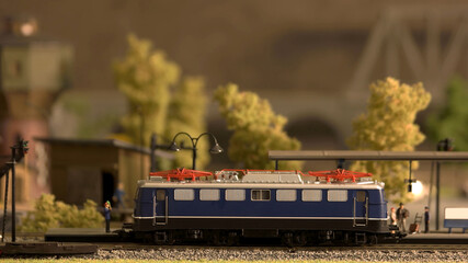 Miniature retro train model on a station Signalman and passangers. Toy plastic railway model.