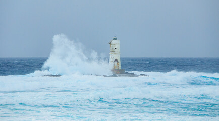 The lighthouse of the Mangiabarche shrouded by the waves of a mistral wind storm
