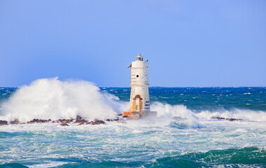 The lighthouse of the Mangiabarche shrouded by the waves of a mistral wind storm
