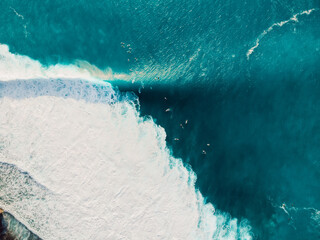 Aerial view of a surfers in blue ocean with waves. Drone view
