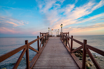 Vista de un muelle en una playa de Marbella al atardecer. Concepto de vacaciones, sol, relax, paisaje.