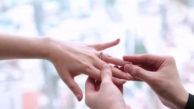Close-Up footage of the groom puts a wedding diamond ring on the bride's finger