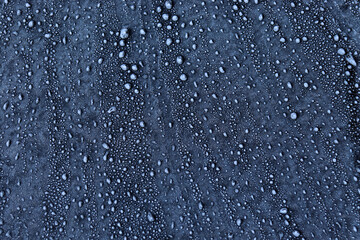 Texture of frozen water drops on a matte surface. Freezing rain. Frost on the glass. Dark blue background. The rocky surface. Stones. Pimples.