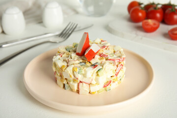 Delicious salad with fresh crab sticks on white table