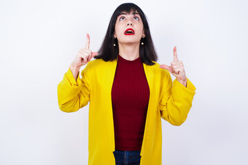 Caucasian woman standing against white background wearing yellow blazer with positive expression,...