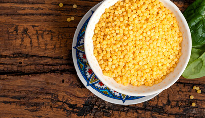 Dry ptitim close-up. Toasted pasta ptitim (petit plomb or Israeli couscous) in a bowl on a wooden background top view.  Copy space.
