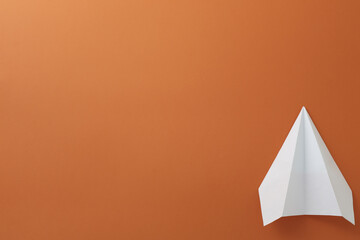 Fototapeta na wymiar Paper white plane on orange background