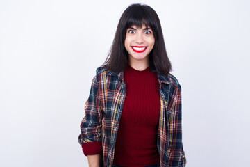 Beautiful young Caucasian woman standing against white background having broad white smile showing white teeth being excited to meet friends.