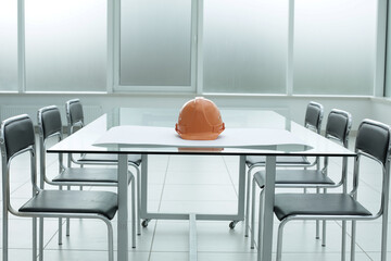 Construction hard hat blueprints on glass table in office space