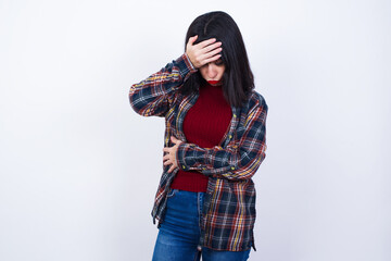 Beautiful young Caucasian woman standing against white background making facepalm gesture while...