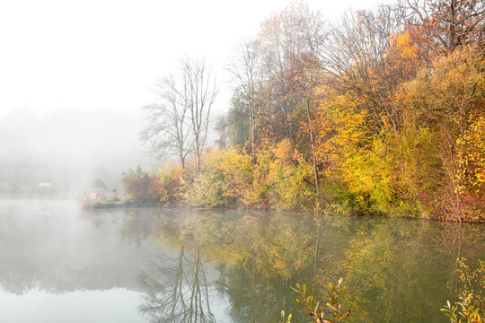 Beautiful landscape with lake and forest. Amazing nature wallpaper. Autumn trees in foggy morning. Romantic place. © romeof