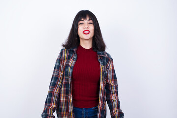 Beautiful young Caucasian woman standing against white background with happy and funny face smiling and showing tongue.