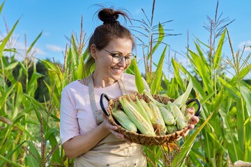 Smiling woman farmer with basket of freshly picked corn