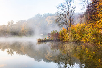 Fototapeta na wymiar Beautiful landscape with lake and forest. Amazing nature wallpaper. Autumn trees in foggy morning. Romantic place. 