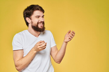 Man gesturing with hands emotions lifestyle white t-shirt yellow isolated background